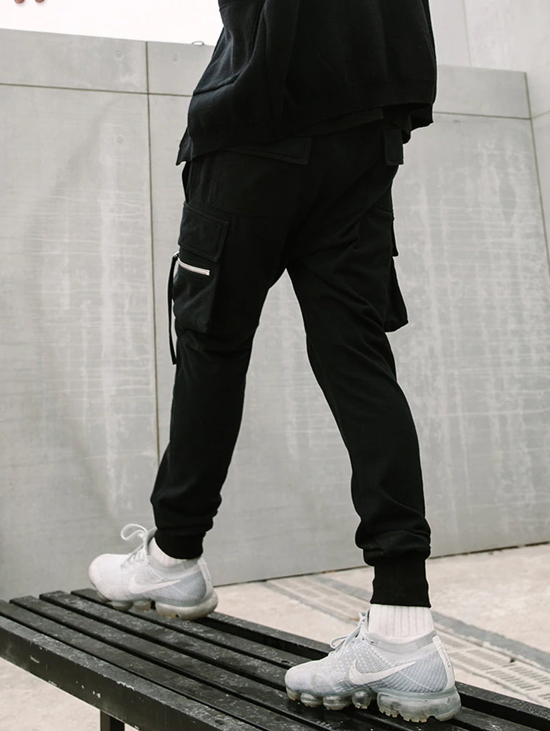 Man  in black cargo pants standing on a bench in an urban environment